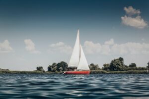 red sail boat on body of water during daytime